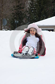 East Indian girl toboganning in the snow