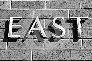 East sign, all caps on a brick wall