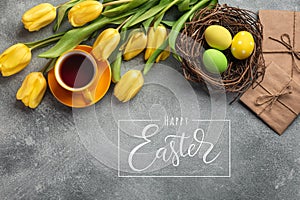 Easter background with blue, green eggs and a cup of tea in nest and yellow tulips. Top view with copy space