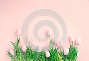 Easter background. Bright pink eggs and vivid spring blooming tulips and fresh grass over pink background