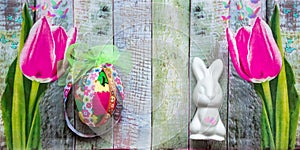 Easter background with bunny, egg and pink tulips on wooden texture. Banner format