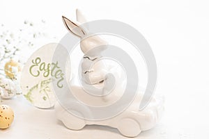 Easter background with a ceramic hare in the car and eggs on a white background,
