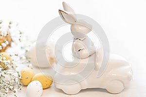 Easter background with a ceramic hare in the car and eggs on a white background,