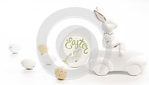 Easter background with a ceramic hare in the car and eggs on a white background,