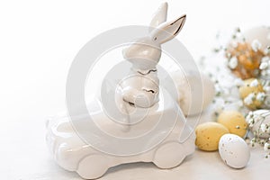 Easter background with a ceramic hare in the car and eggs on a white background,