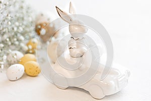 Easter background with a ceramic hare in the car and eggs on a white background,