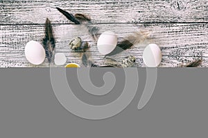 easter background with chicken quail one broken eggs and feathers on white wooden table, food top view