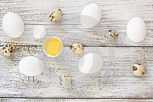 easter background with chicken quail one broken eggs on white wooden table, food top view