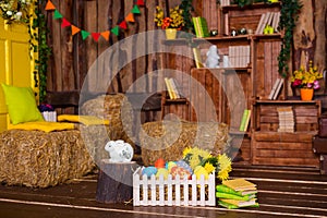 Easter background with colorful eggs, white bunny and yellow flowers over old wood.