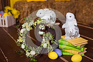 Easter background with colorful eggs, white bunny and yellow flowers over old wood. Top view with copy space