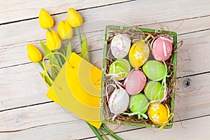 Easter background with colorful eggs and yellow tulips