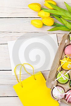 Easter background with colorful eggs, yellow tulips and greeting