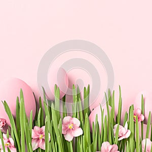 Easter background with Easter eggs in grass with flowers on pink.