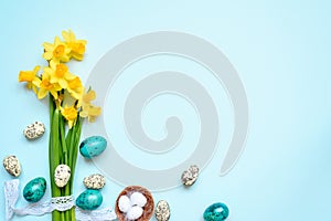 Easter Background with easter eggs and spring flowers on blue background. top view