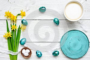 Easter background with easter eggs, spring flowers, cup of cappuccino and and empty blue plate