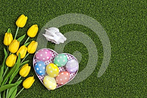 Easter background with eggs, buny and yellow tulips on a green grass photo