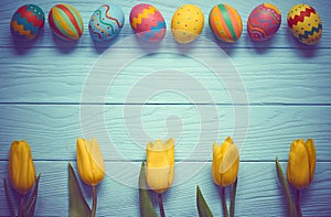 Easter background, eggs, yellow tulips on wood