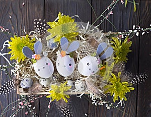 Easter background, homemade eggshell bunnies and yellow chrysanthemum in wooden box