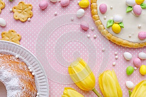 Easter background with marzipan eggs, easter cakes and spring flowers on on a pink background