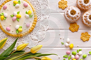 Easter background with marzipan eggs, mazurek pastry, yeast cakes, spring flowers