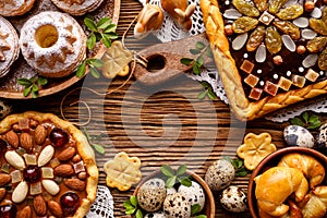 Easter background with  mazurek pastry, yeast cakes and quail eggs on rustic wooden background