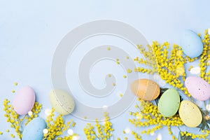 Easter background with mimosa flower and colorful eggs. Spring greeting card. Space for text.