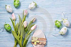 Easter background with pink tulips and easter eggs, wooden background, top view