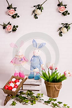 Easter background with pink and white tulips, toy bunnies and red eggs.