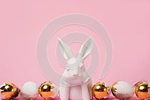 Easter background with white bunny and golden eggs, copy space . Easter greeting card