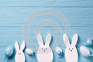 Easter background with white rabbits and easter eggs, wooden background, top view with copy space