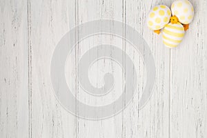 Easter background white wooden table with eggs and dry yellow spring flowers and copy space