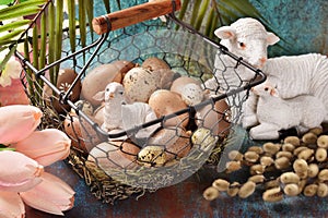 Easter background with a wire basket full of eggs, lamb figurines and catkins