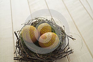 Easter background with yellow eggs in the nest on wooden table.