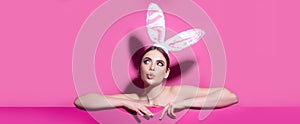 Easter banner with bunny woman. Easter young woman studio wearing bunny ears. curious isolated on pink.