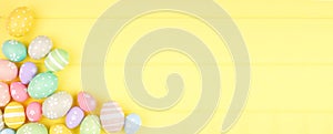 Easter banner with corner border of pastel Easter Eggs over a yellow wood background with copy space