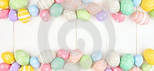 Easter banner with double border of pastel Easter Eggs over a white wood background with copy space
