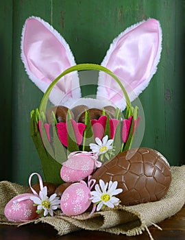 Easter basket with bunny ears and chocolate Easter eggs