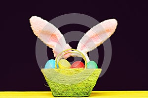 Easter basket with colored Easter eggs and pink bunny ears