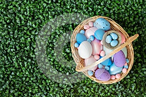 Easter basket with eggs on green lawn. Easter composition. Festive egg hunt. Copy space, top view, flat lay