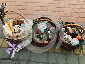 Easter baskets with stylish painted eggs, easter cake, ham,beets, butter, candle with boxwood branches for sanctify at church. photo