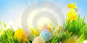 Easter. Beautiful colorful eggs in spring grass meadow over blue sky with sun border design