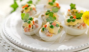 Easter boiled eggs stuffed with traditional  vegetable salad with mayonnaise served on a white plate