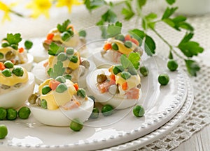 Easter boiled eggs stuffed with traditional  vegetable salad with mayonnaise served on a white plate