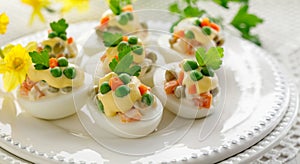 Easter boiled eggs stuffed with vegetable salad with mayonnaise served on a white plate