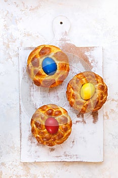 Easter bread with colored eggs on rustic  kitchen board