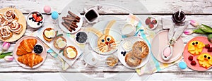 Easter breakfast or brunch table scene. Overhead view on a white wood banner background.