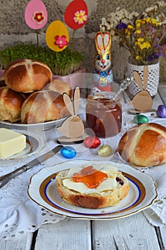 Easter breakfast with traditional hot cross buns, jam, butter and egg. Holiday still life. Festive table place setting decoration