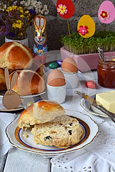 Easter breakfast with traditional hot cross buns, jam, butter and egg. Holiday still life. Festive table place setting decoration