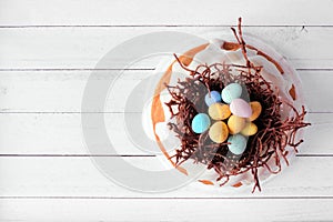 Easter bundt cake with chocolate nest of candy eggs, above on a white wood