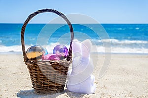 Easter bunny with basket and color eggs on the ocean beach